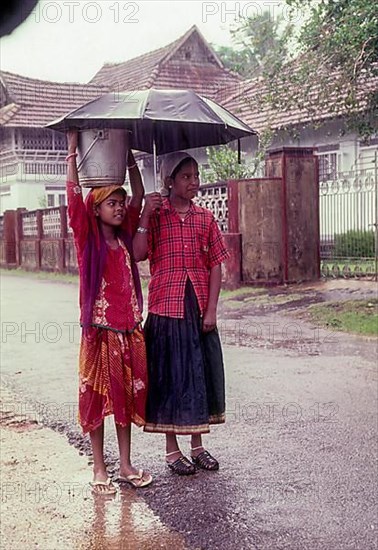 Two girl children with umbrella on a rainy day in Kottayam