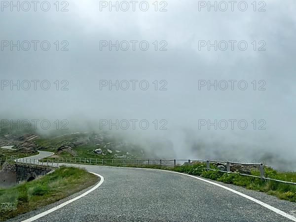 Low clouds over winding mountain road Pass road to Colle del Nivolet