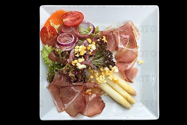 Asparagus salad with ham on a black background