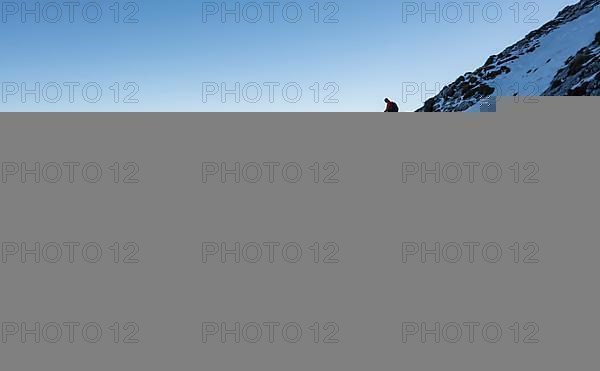 Mountaineers on the rocky summit ridge with the first snow in autumn