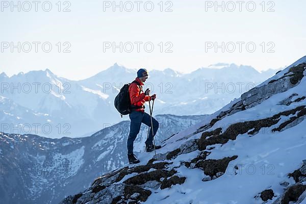 Mountaineers on the rocky summit ridge with the first snow in autumn