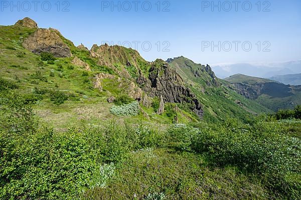 Mountain landscape with green overgrown furrowed volcanic tuff rocks