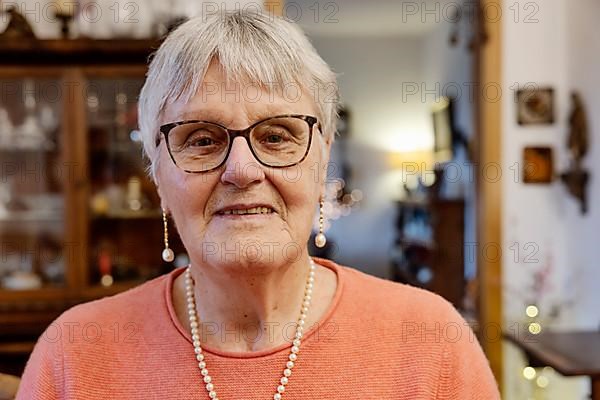 Portrait of a senior woman with glasses looking into the camera at home