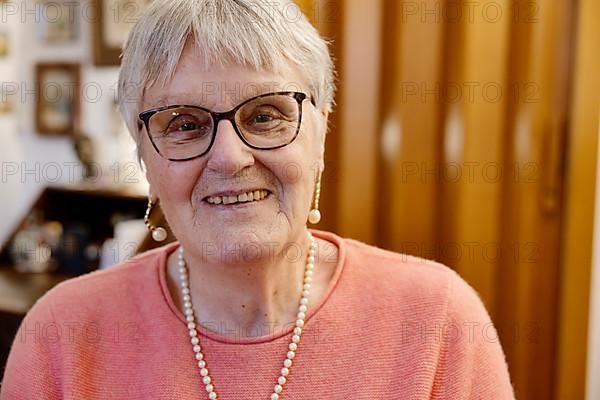 Senior woman with glasses laughs into the camera