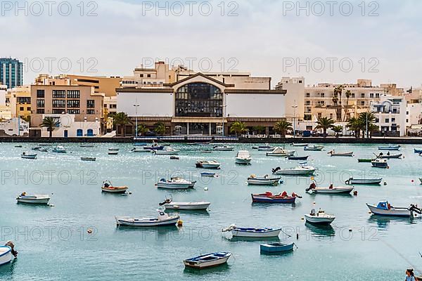 Beautiful quay with historic architecture and boats on blue water in Arrecife