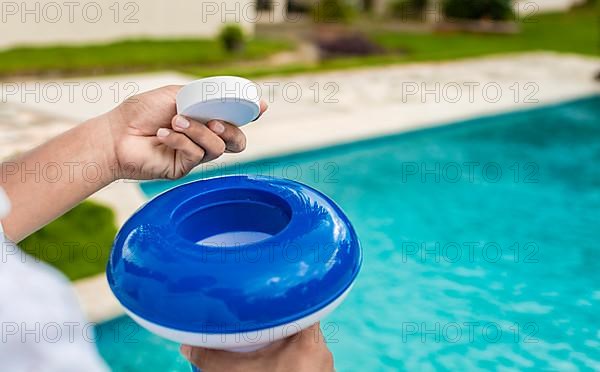 Hands holding a dispenser with pool chlorine tablet