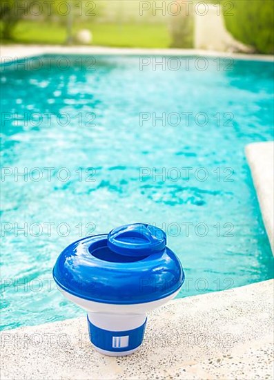 A chlorine float on the edge of a swimming pool. A chlorine dispenser for swimming pools with blue water in the background. Dosing float for swimming pool chlorination