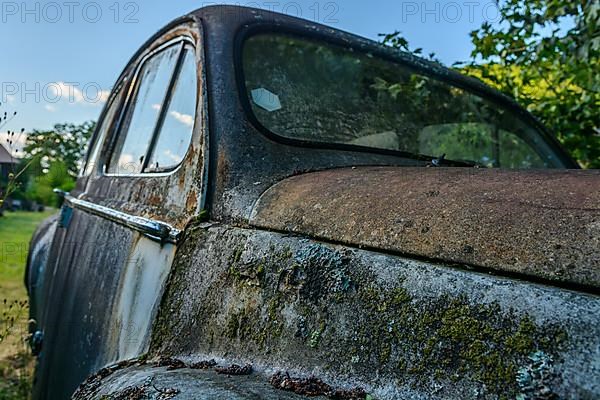 Old car rolled for scrapping in a meadow. Alsace