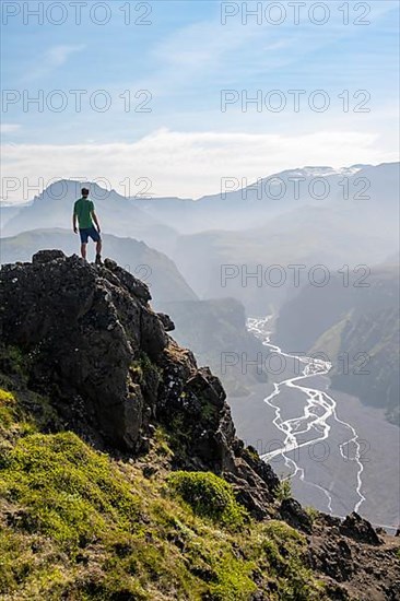 Hiker on a rock in front of mountain landscape