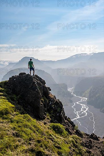 Hiker on a rock in front of mountain landscape