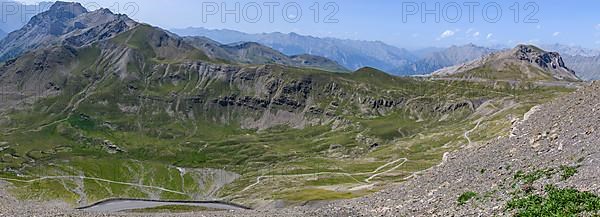 View from Cime de la Bonette on high alpine mountain landscape with road to Col de la Bonette in the background on the right