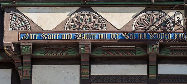 Coloured carving and saying 'Honour father and mother with deed