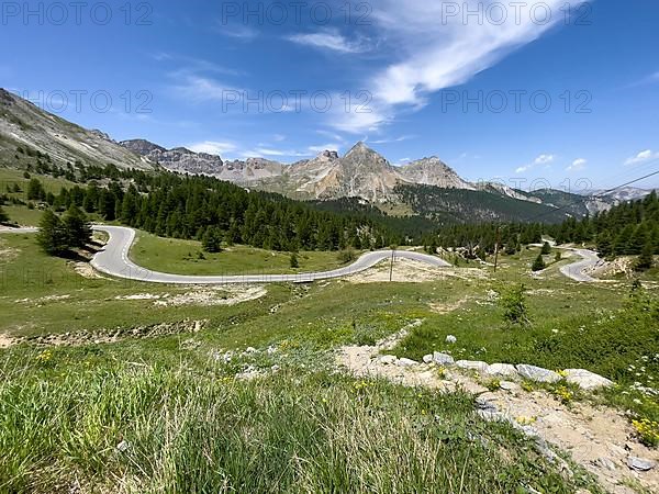 View over wild alpine meadow on winding alpine road Mountain road in front of Col de l Izoard