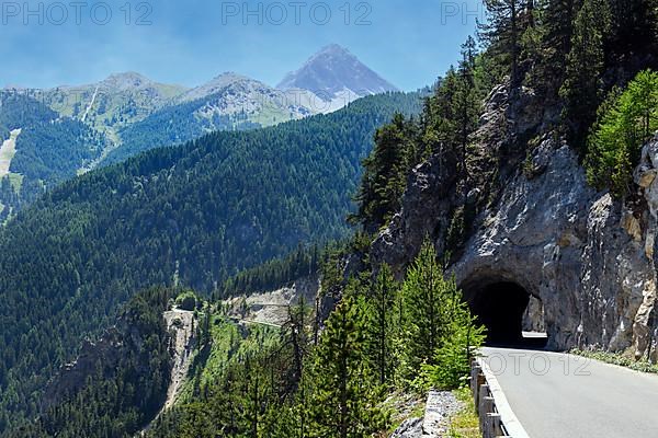 Mountain road with tunnel on steep rock face with tree cover