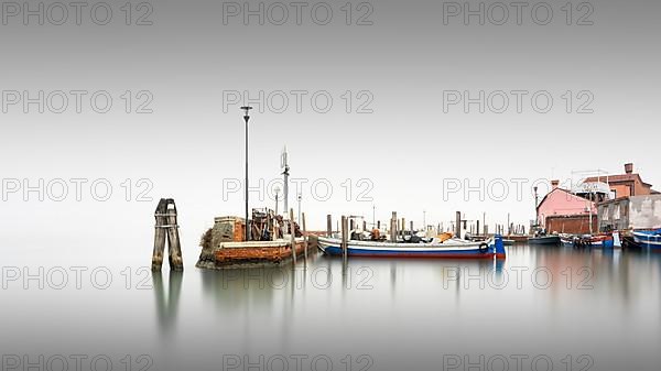 Classic harbour view of the small port of Burano in the fog in Italy