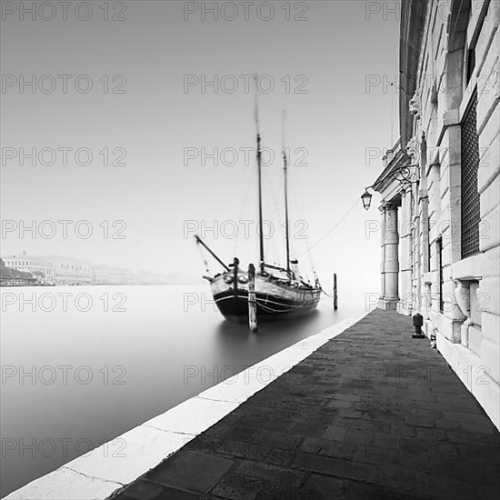 Black and white photograph of the Fondamenta Salute in the fog with a historic sailing ship in Venice