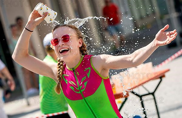 A runner refreshes herself with a cup of water at the 27th city triathlon in Erding