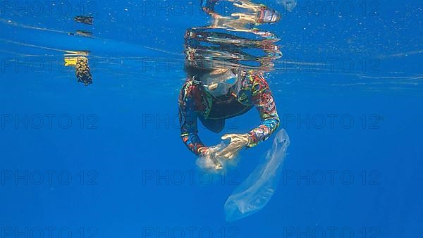 Woman collects plastic garbage underwater clean up of a dirty discarded plastic bags