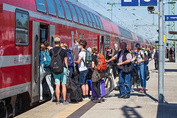 Many people standing crowded on a platform in front of a local train