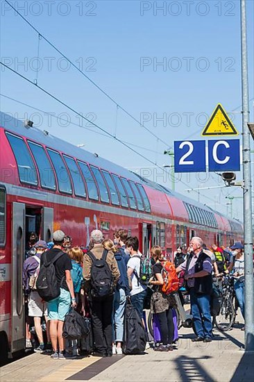 Many people standing crowded on a platform in front of a local train