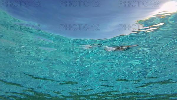 Sunlight rays shining through blue ocean surface. Natural underwater background. Backlight