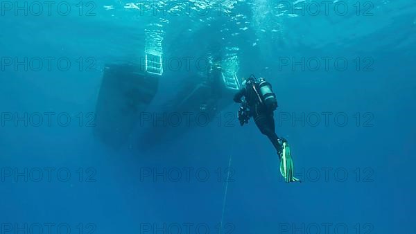 Scuba diver swim towards diving boat in blue water. Mediterranean Sea