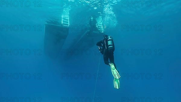Scuba diver swim towards diving boat in blue water. Mediterranean Sea