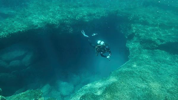 Female scuba diver near the exit from the cave. Cave diving in Mediterranean Sea
