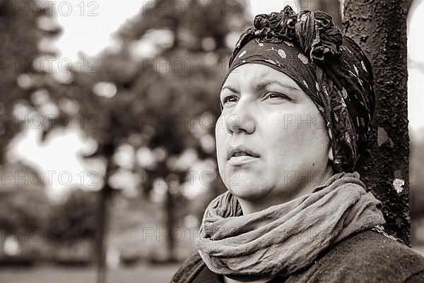 Woman with cancer in headscarf outdoors. Black and white shoot