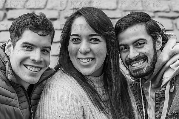 Portrait of three happy friends in black and white. They are looking at the camera