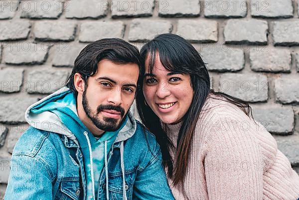 Happy couple sitting outdoors while looking at camera