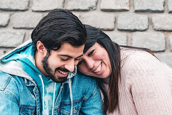 Happy couple talking outdoors. She puts her head on his shoulder