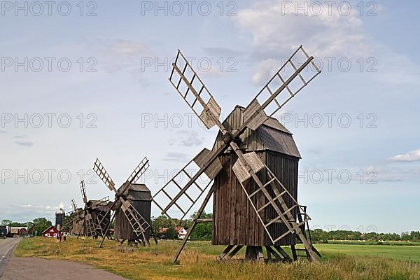 Several wooden mills standing by a road