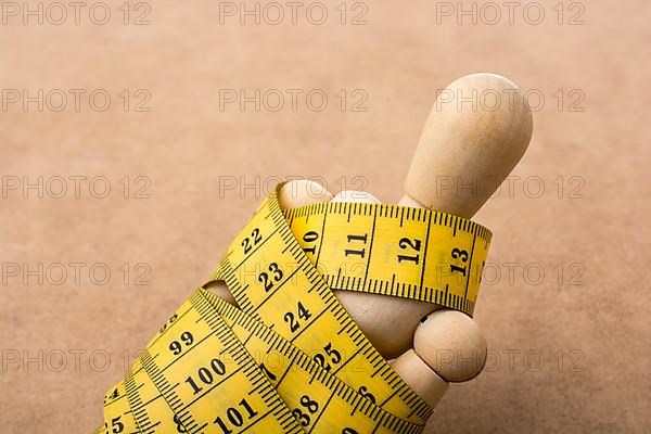 Yellow color measuring tape wrapped on wooden man