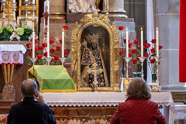 Worshippers sit in front of the Black Madonna in the collegiate parish church of St. Philip and St. James in the pilgrimage town of Altoetting. The image of grace is normally in the Holy Chapel