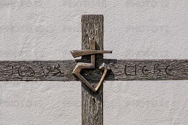 Wooden cross with metal emblem and the words 'Love' and 'Jesus' carved into wood