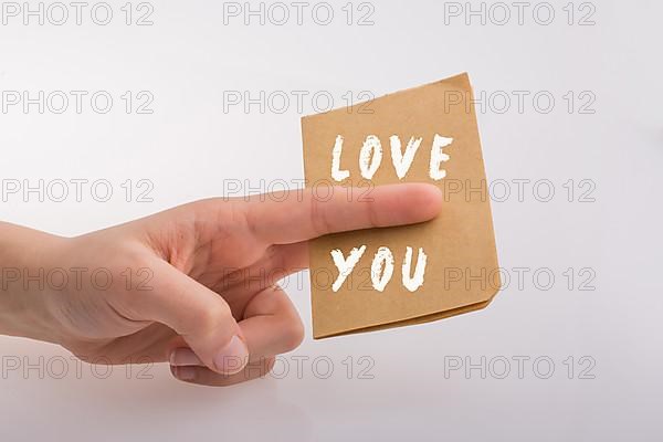 Love You text on paper in hand over white background