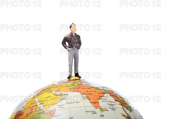 Man figurine standing at the top of a globe on a white background