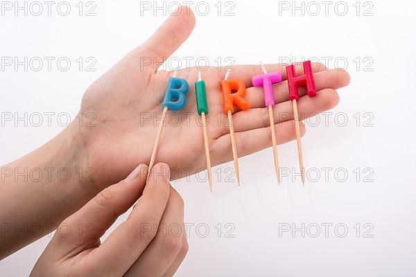 Color candles in hand on sticks write the word birth