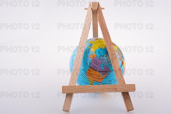 Little model globe put under tripod on a white background