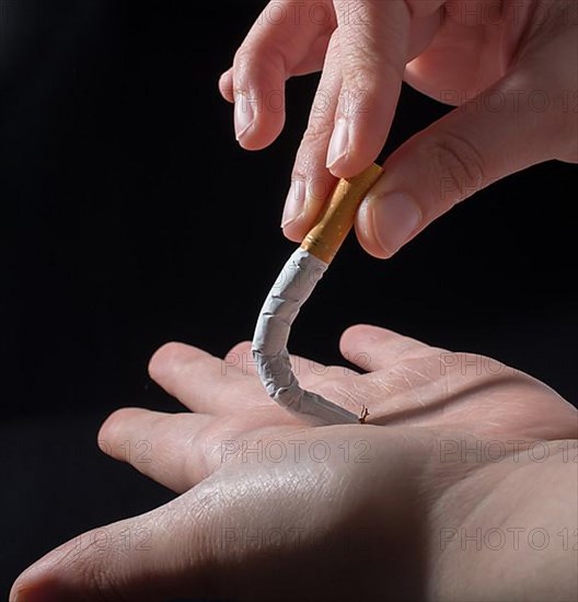 Hand is breaking a cigarette on a black background