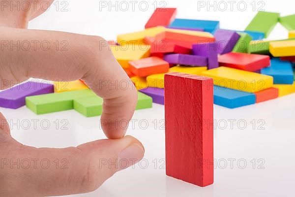 Hand playing with colored domino on white background