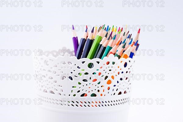 Colorful pencils in a vase on a white background