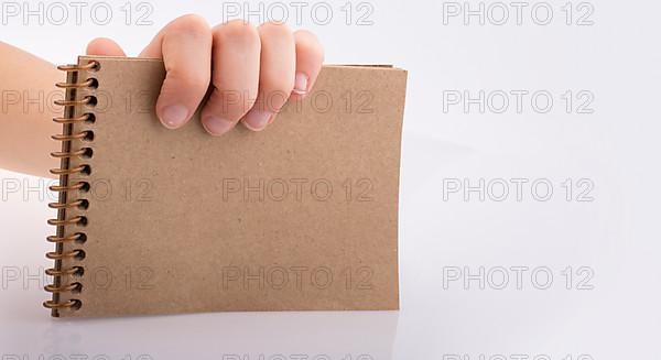 Hand holding brown color notebook on a white background