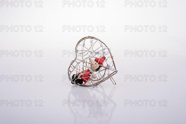 Wooden Pinocchio doll sitting in a heart shaped cage