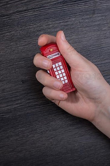 Hand holding a phone booth on a dark background