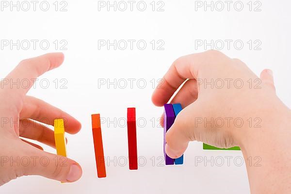 Hand playing with colored domino on white background