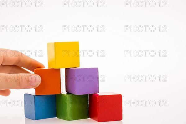 Hand playing with colorful cubes on a white background