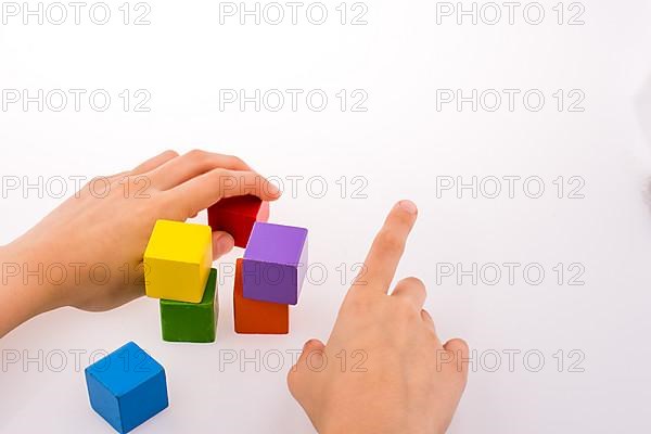 Hand playing with colorful cubes on a white background