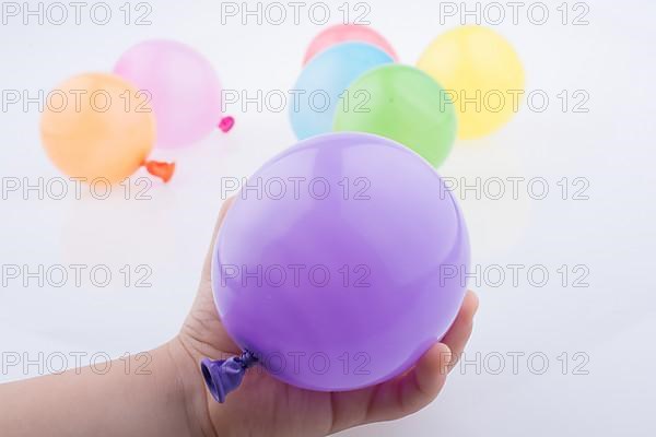 Hand holding a Colorful small balloon with colorful baloons on the white background